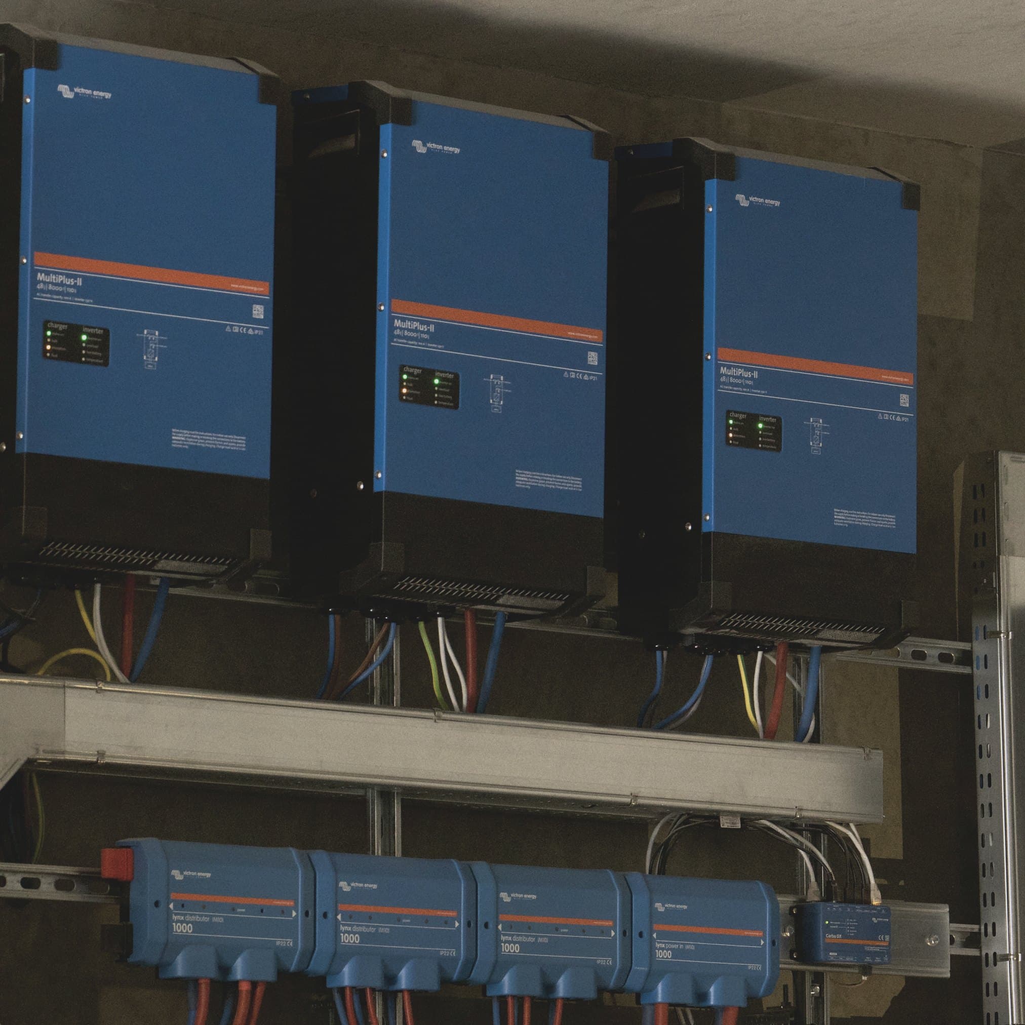 Three Victron MultiPlus-II inverters mounted above Lynx distributors in a home technical room.
