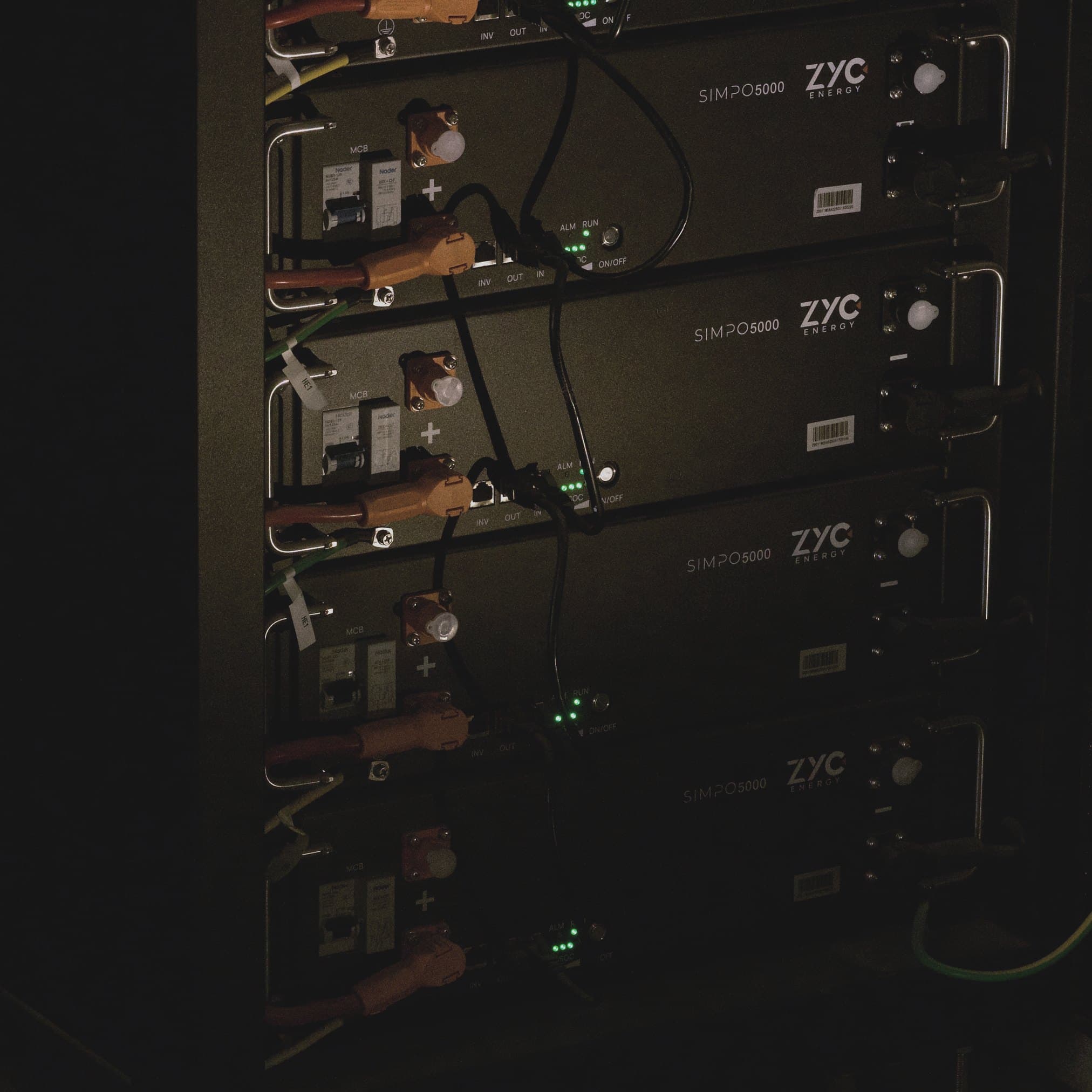 An open energy storage cabinet with battery modules next to Victron MPPT charge controllers.