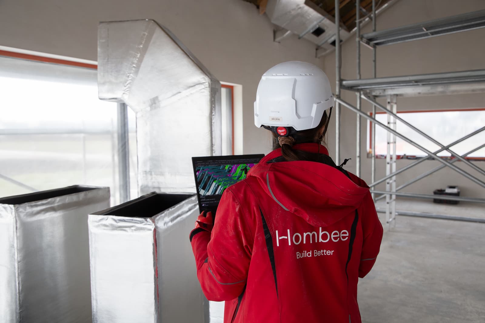 A Hombee specialist checking a building services model on a laptop inside a construction site.