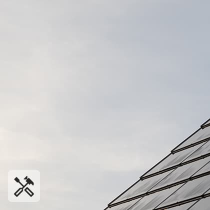 A close-up of a pitched roof covered with dark, integrated photovoltaic panels that form a smooth, uniform surface.