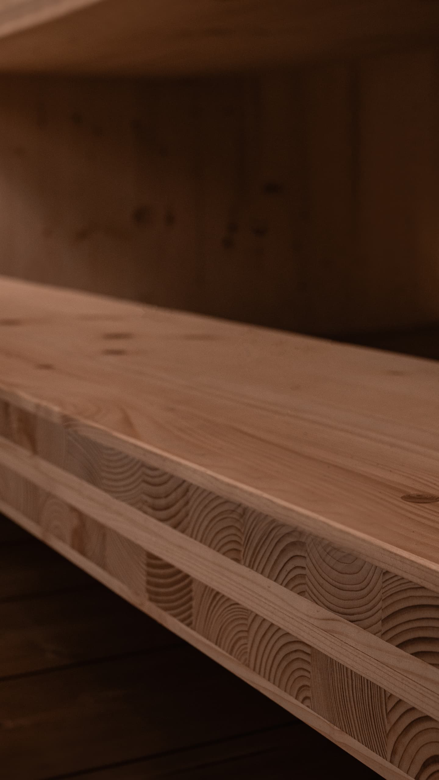 An angular close-up of a solid light wood beam in a sauna, showing its layered construction of glued beams and visible grain.
