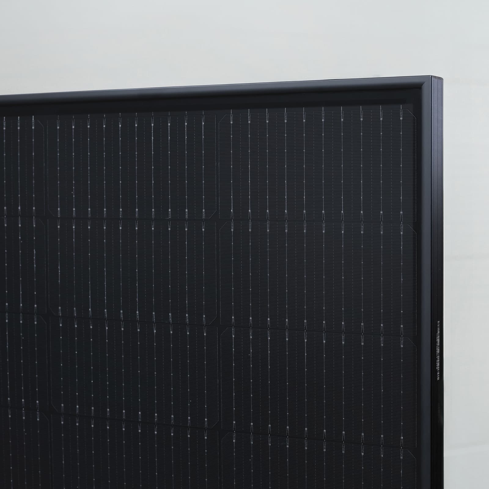 A close-up of a pitched roof covered with dark, integrated photovoltaic panels that form a smooth, uniform surface.