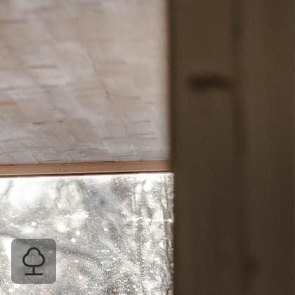 A shot of the interior of a room finished in light wood, showing a corner and a large window with a view of a snowy landscape.