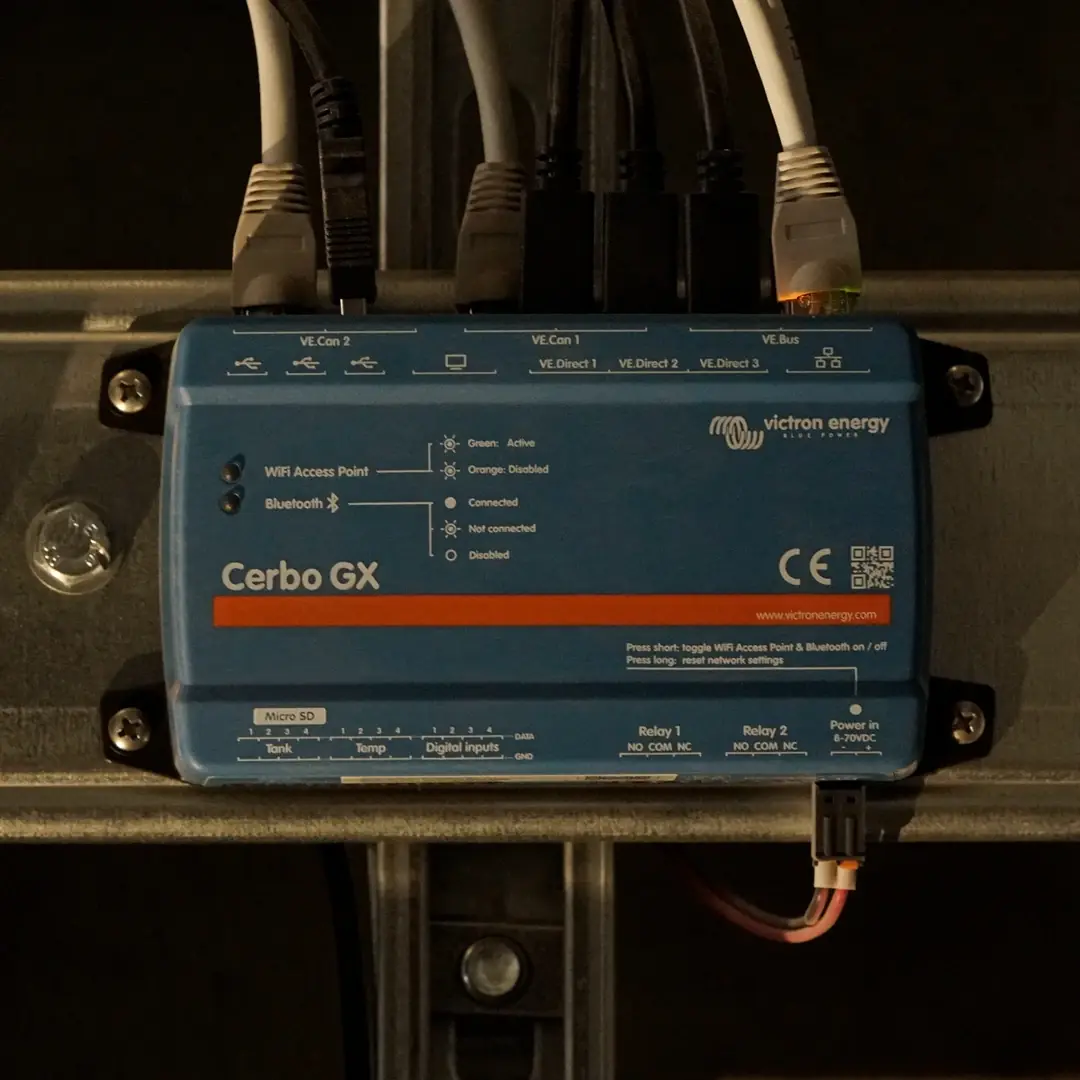 A Victron Cerbo GX controller on a DIN rail with communication cables connected.