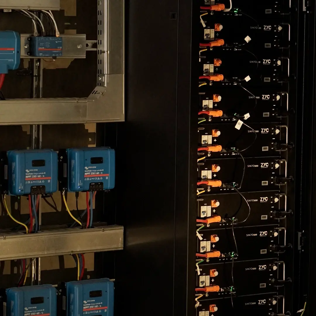 ZYC Energy battery modules in an energy storage cabinet next to Victron SmartSolar MPPT charge controllers.